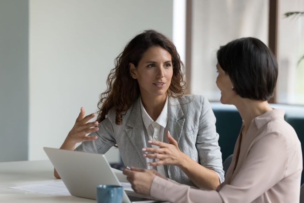 2 women talking around a laptop