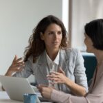 2 women talking around a laptop